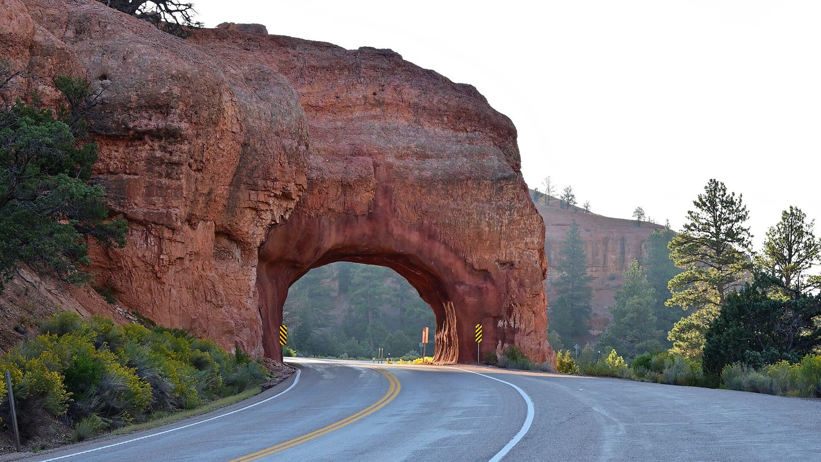 Utah State Route 12 passing through the Red Canyon Arch tunnel with the glow of sunrise behind the arch. (Note: EXIF time is Eastern Dayligh